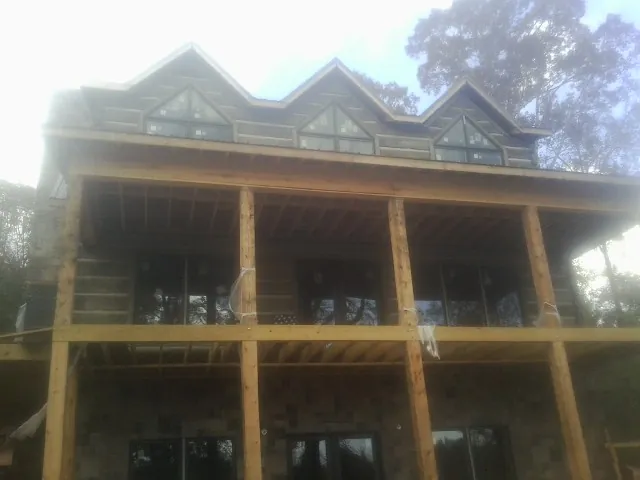 Dormers and porch framing on a large log home under construction — Roof Coating work by our crew in Baton Rouge