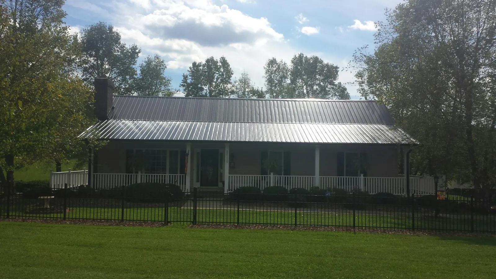 Gray metal roof on a brick ranch with a full width front porch — Gutter Guard Installation work by our crew in Baton Rouge
