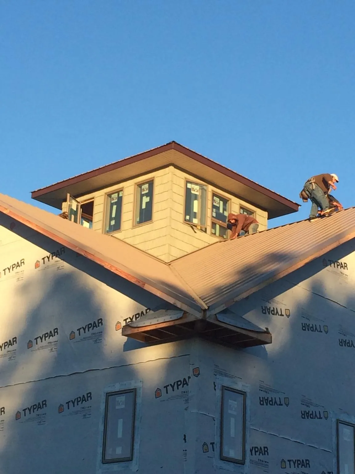 Roofers working around a rooftop cupola on a new metal roof at sunset — Roof Waterproofing in Baton Rouge by Roofing Brothers
